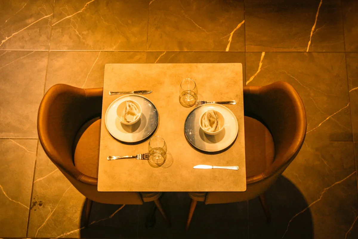 An overhead restaurant table where the plates, glassware, wood, and leather chairs all carry the same warm palette