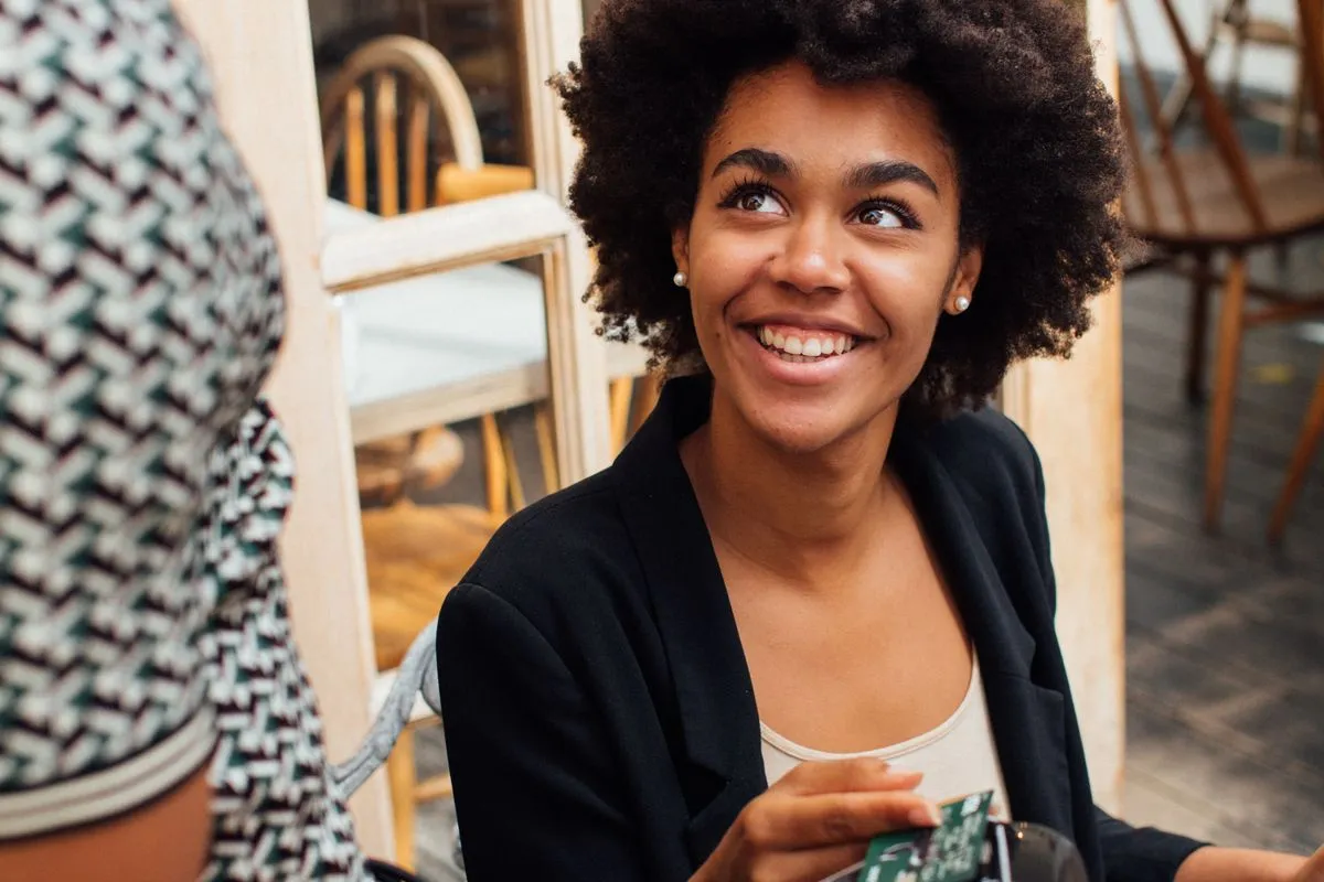 A smiling guest handing a card to a server at a cafe table