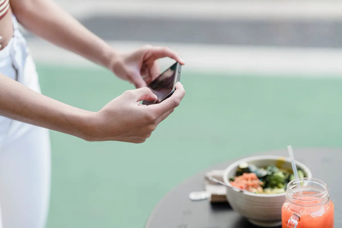 A content creator photographing a plated dish on a phone at a table