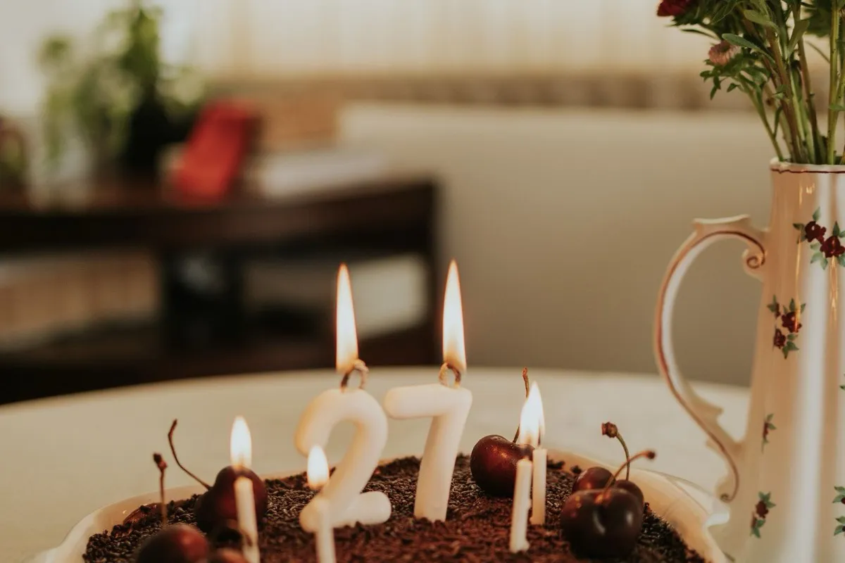 A birthday cake with a lit candle on a table, the reward that brings regulars back on their birthday