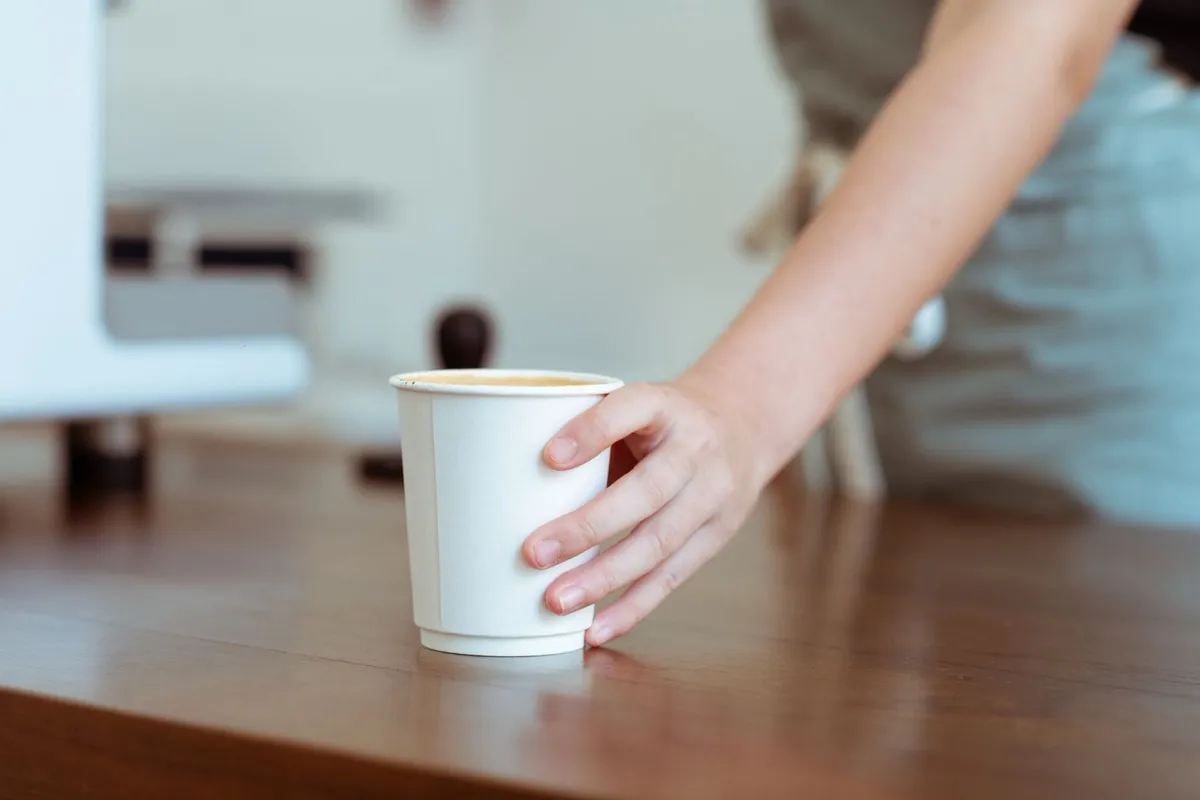 A barista serving coffee at the counter, the kind of repeat visit a punch card is built to reward