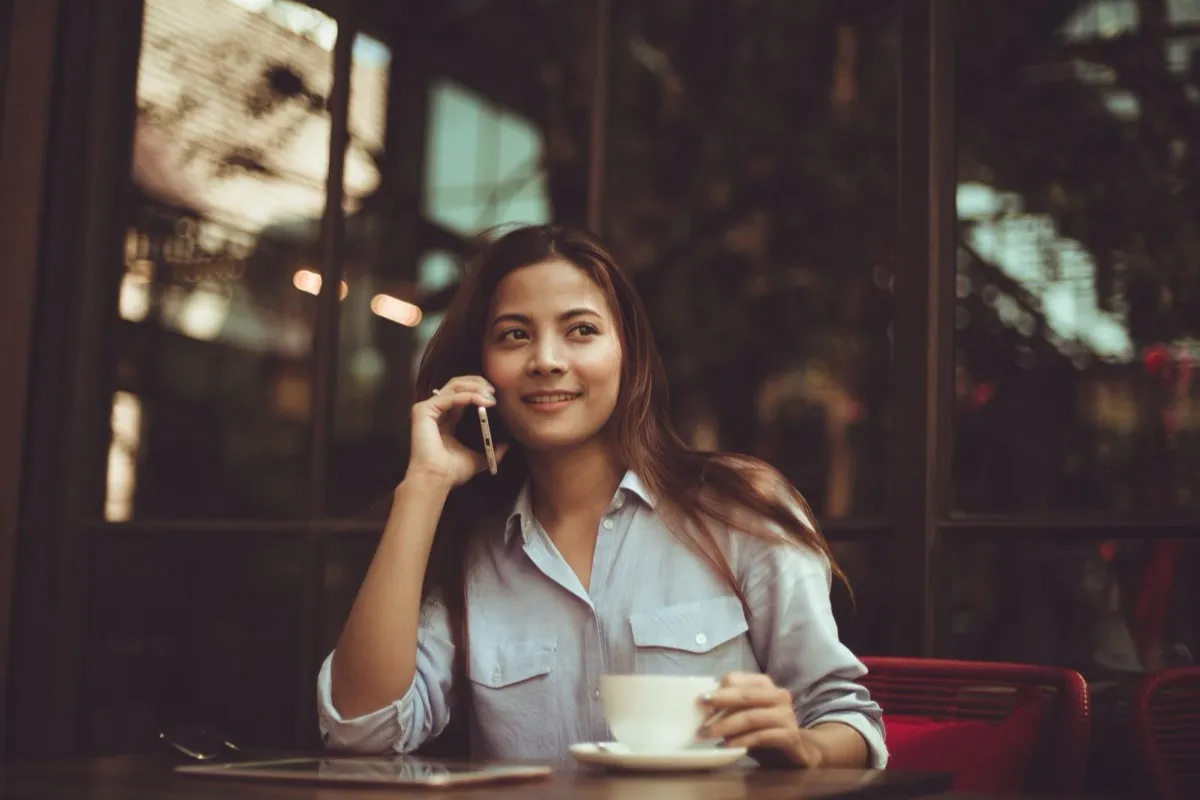 A cafe guest on her phone with a coffee, the direct line an owned loyalty list gives you