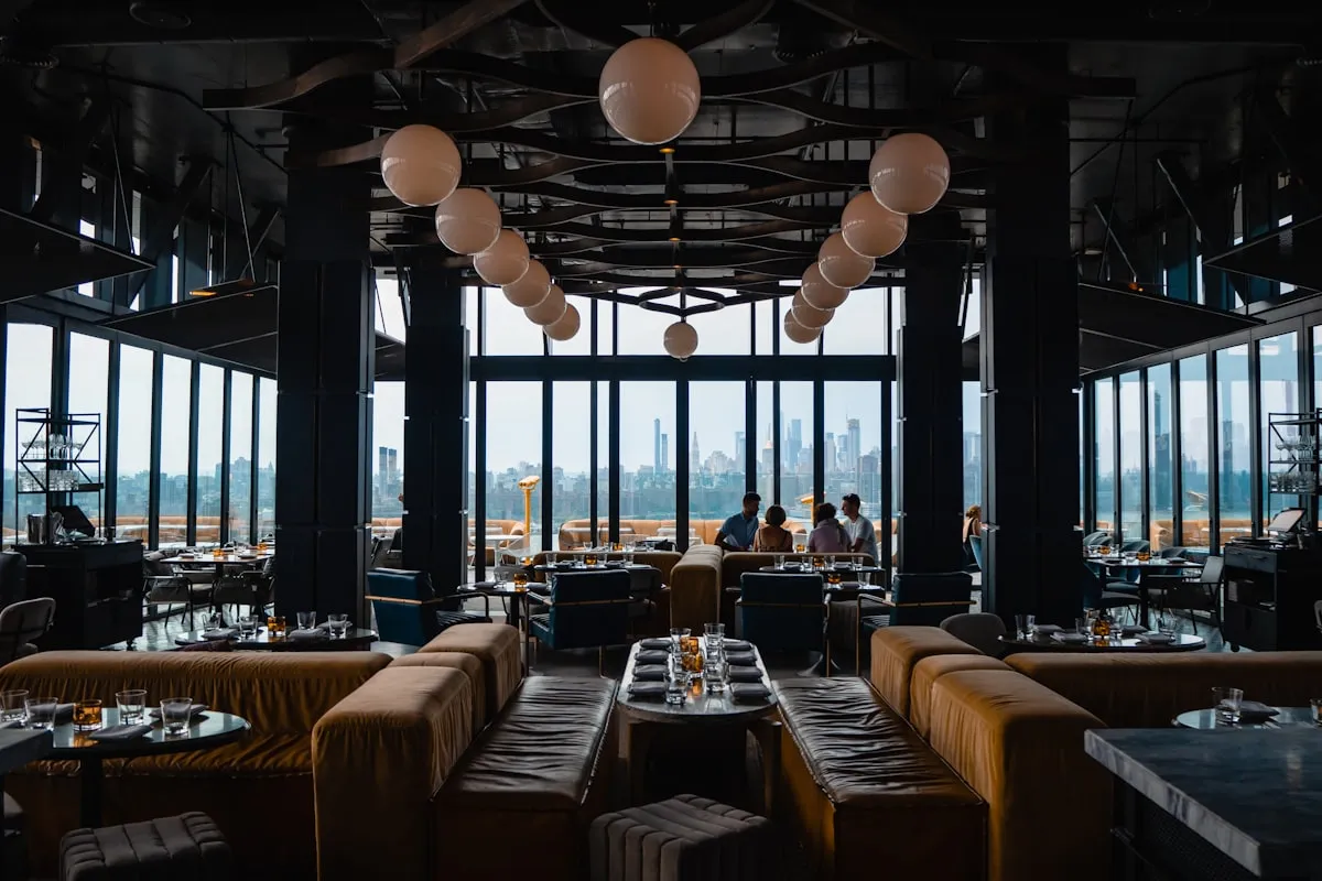 A large, elegant, nearly empty restaurant dining room at dusk
