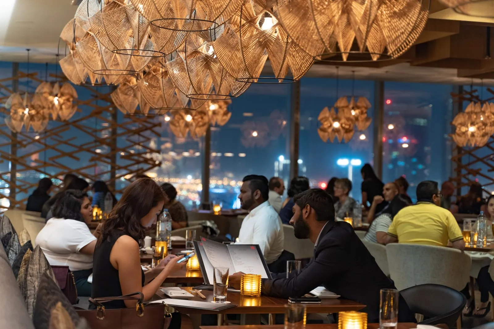 A warm, busy restaurant dining room full of guests at night