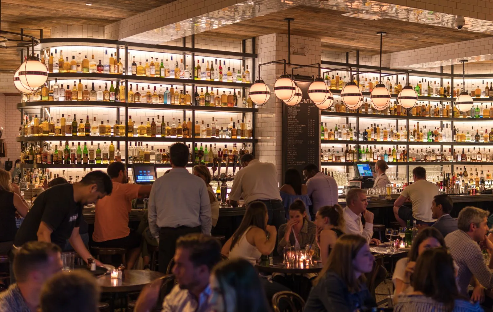 A warm, busy restaurant bar full of guests
